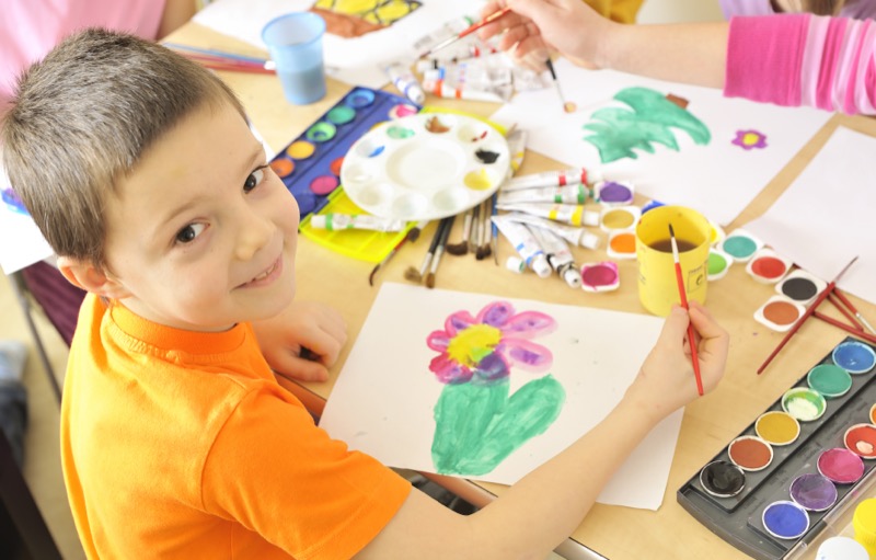 La imagen muestra a un niño realizando un dibujo con tempera