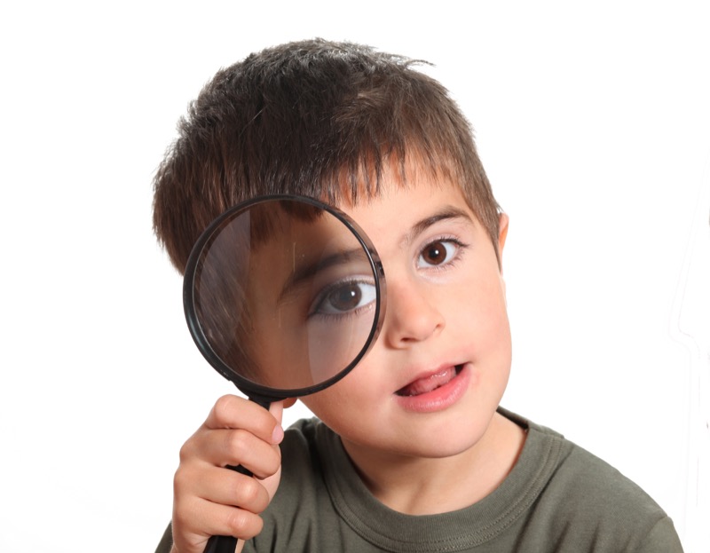 La imagen muestra a un niño con una lupa en el ojo