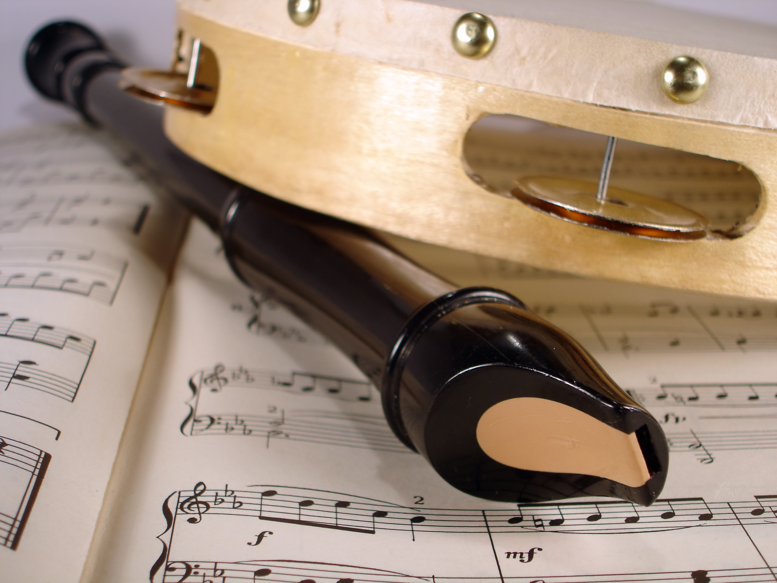 La imagen muestra un a flauta y un pandero sobre unas partituras