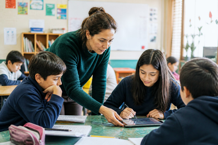 Fotografía de profesora trabajando colaborativamente con sus estudiantes.