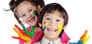 Imagen de una niña y un niño felices, con las manos y caras pintadas de colores.