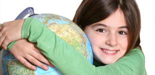 La imagen muestra a una niña abrazando un globo terráqueo