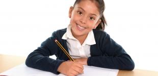 La imagen muestra a una niña sonriente escribiendo en un cuaderno