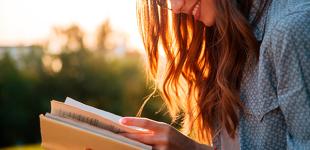 Mujer joven leyendo un libro al aire libre