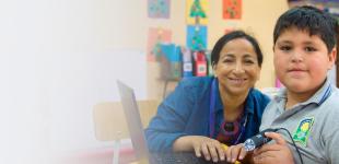 Fotografía de profesora estudiante varón mirando sonrientes hacia la cámara.
