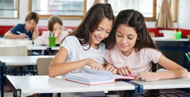La imagen muestra a dos adolescentes leyendo un libro