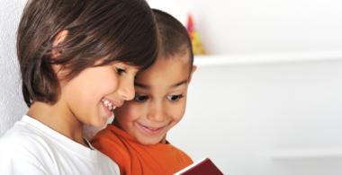 Dos niños pequeños leen un libro 