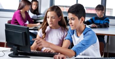 En la imagen se observa a dos jóvenes que trabajando frente a un computador 