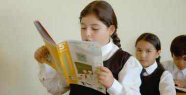 La imagen muestra a una niña leyendo una fábula
