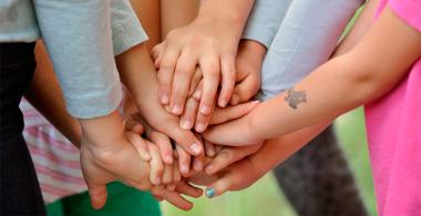 Manos de varios niños están una encima de la otra