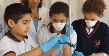 la imagen muestra a 3 alumnos realizando un experimento