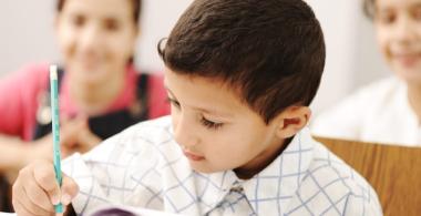 La imagen muestra a un niño escribiendo