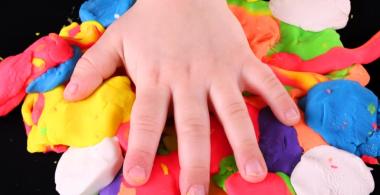 Imagen que muestra una mano de niño o niña encima de varias  plasticinas