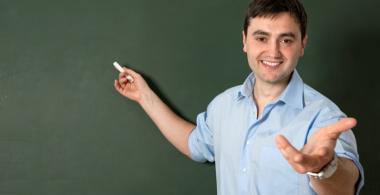 Imagen de un profesor sonriendo y escribiendo en un pizarrón.
