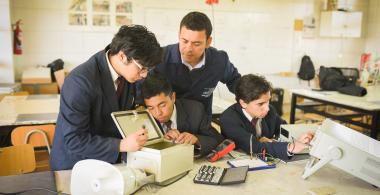 Tres alumnos trabajan junto a su profesor en el desarrollo de una alarma barrial