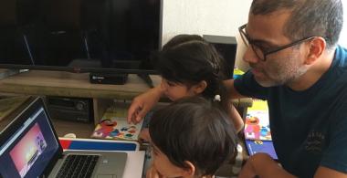 Padre y sus hijos pequeños viendo una película educativa online