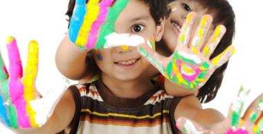 La imagen muestra a dos niños con sus manos pintadas 