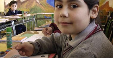 La imagen muestra a una niña en primer plano realizando una actividad en sala de clases