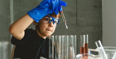 La imagen muestra a un niño experimentando con tubos de ensayo