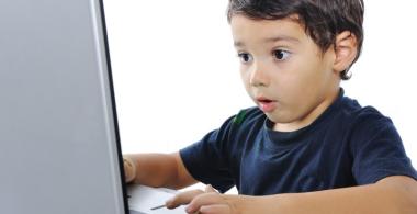 La imagen muestra a un niño sorprendido observando algo en un notebook