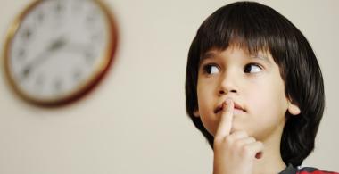 La imagen muestra a un niño con el dedo sobre la boca y los ojos mirando hacia el lado, pensando en algo