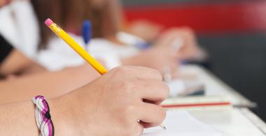 La imagen muestra estudiantes escribiendo textos