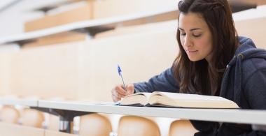 La imagen muestra a una estudiante leyendo y escribiendo un texto