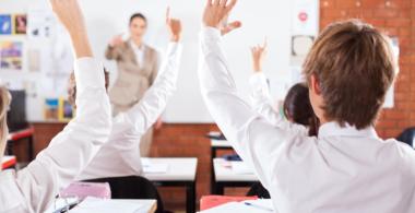 La imagen muestra una sala de clases con alumnos participando