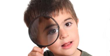 La imagen muestra a un niño con una lupa en el ojo