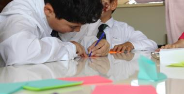 niño escribiendo en papeles de colores