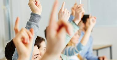 Estudiantes levantando la mano para opinar