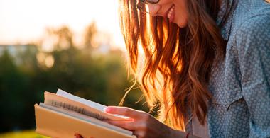 Mujer joven leyendo un libro al aire libre