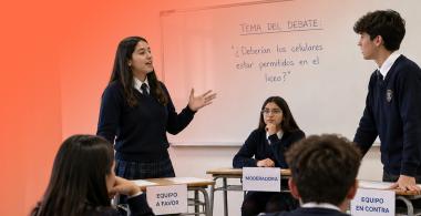 Grupo de estudiantes de educación media debatiendo en sala de clases.