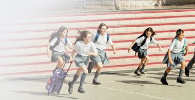 Ninos y niñas vestidos con uniforme escolar corriendo hacia la misma dirección.